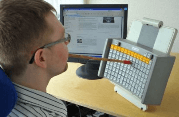 Man with motor impairment using a stick to type