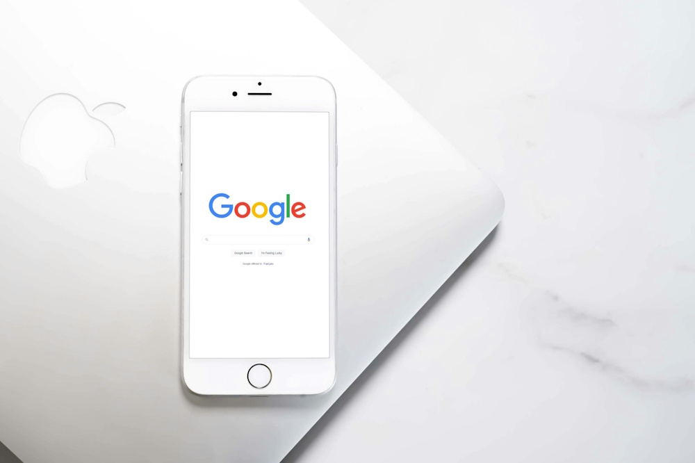 a smartphone lying on top of a laptop with Google on the screen