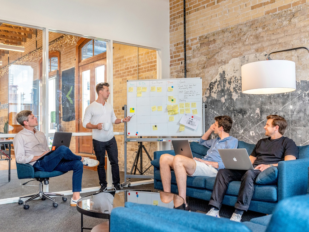 group of men listening to a presentation by their leader in a small boardroom